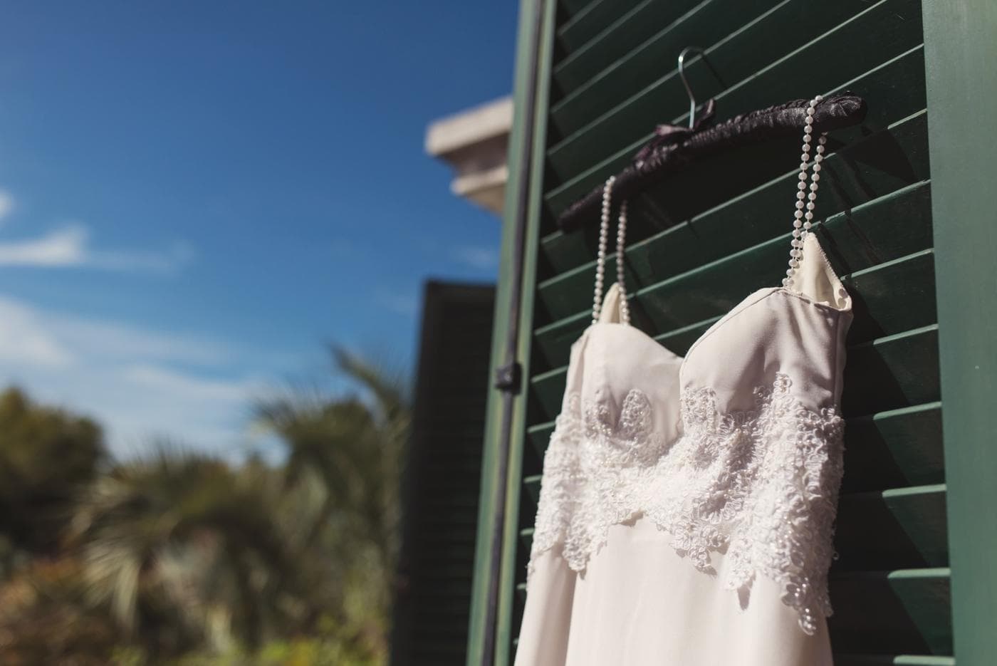 Vestido de novia colgado de un postigo verde