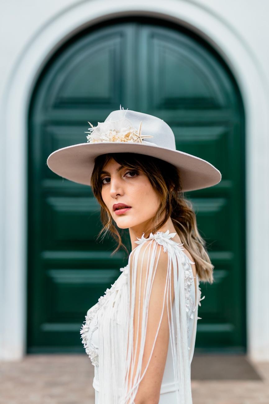Novia con sombrero frente a la puerta verde de arco